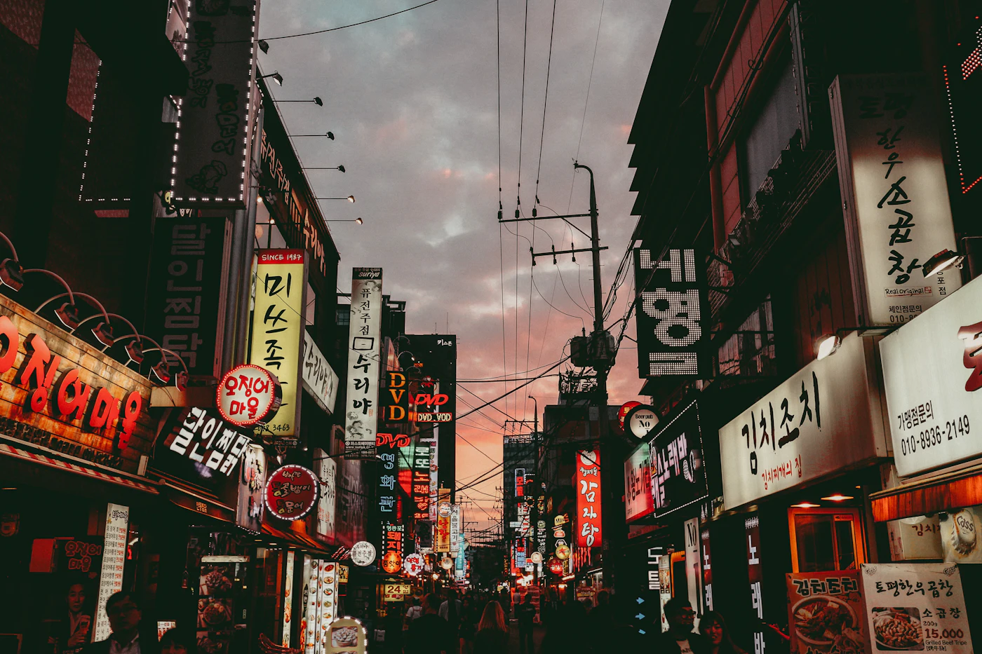 A street of small restaurants in Seoul at dusk, every sign in Korean
