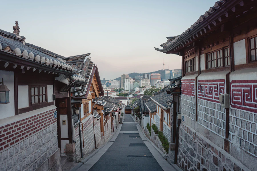 A narrow hanok alley in Bukchon, Seoul, with the city skyline behind